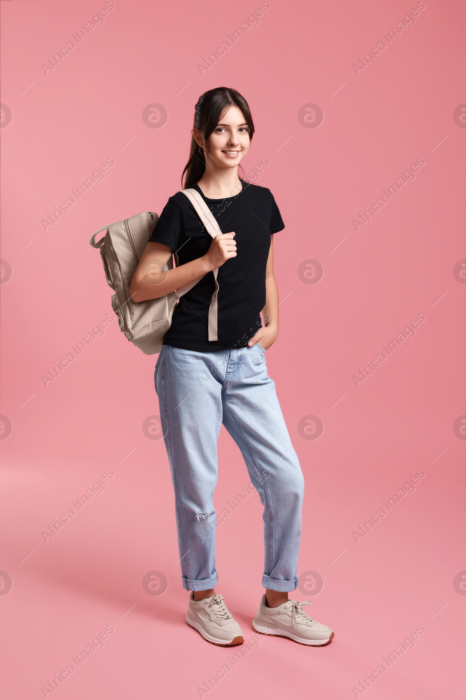 Photo of Cute teenage girl with backpack on pink background