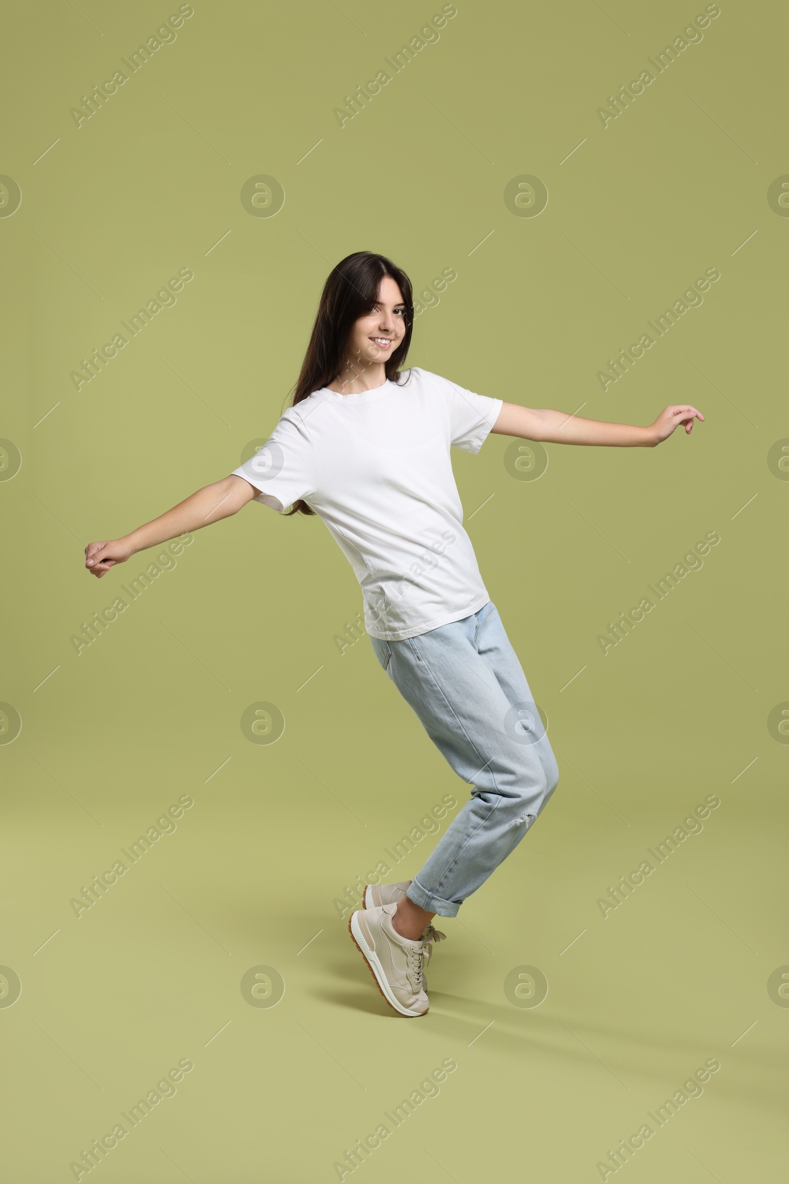 Photo of Cheerful teenage girl dancing on olive background