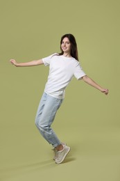 Photo of Cheerful teenage girl dancing on olive background