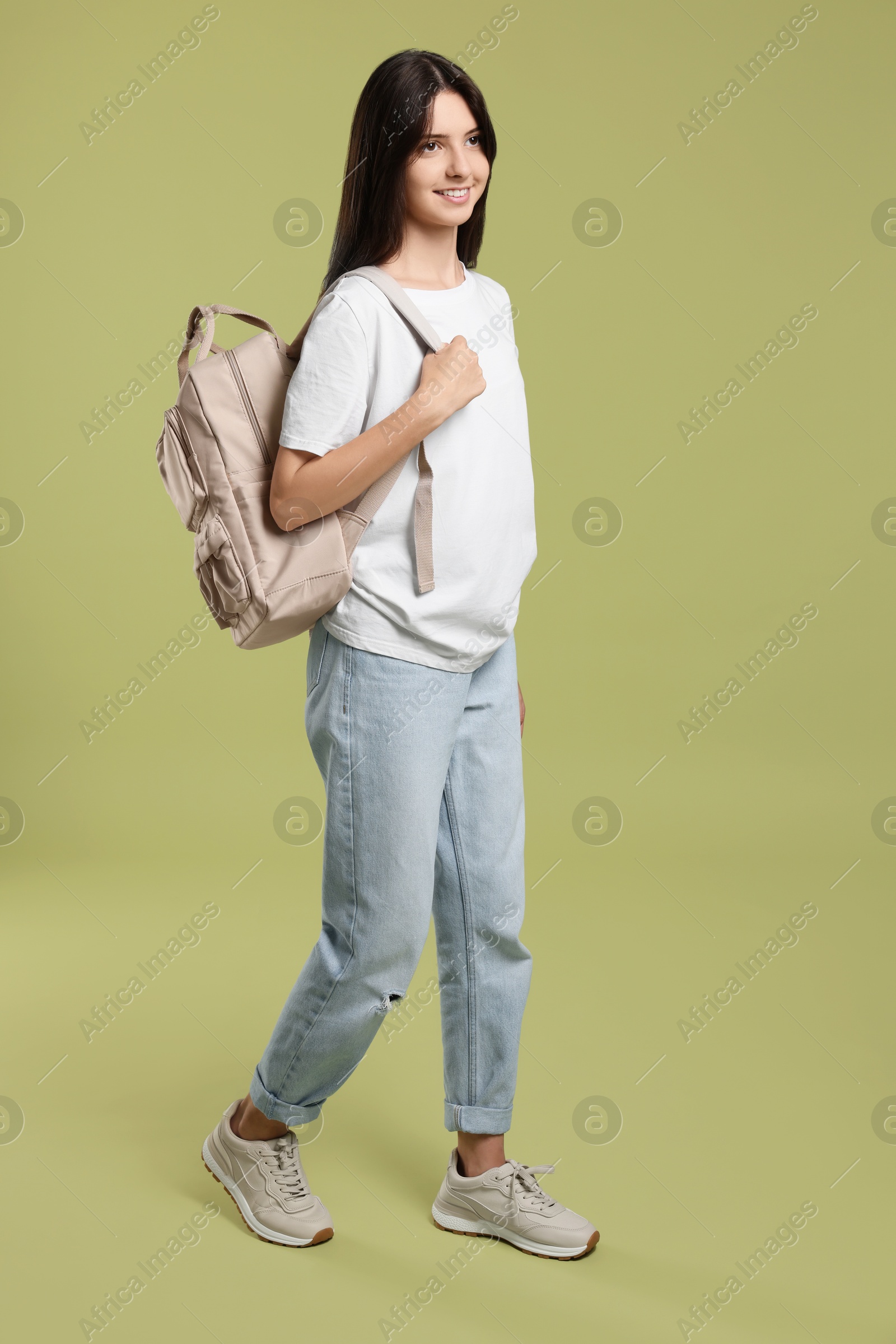 Photo of Cute teenage girl with backpack on olive background