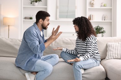 Photo of Emotional couple arguing on sofa at home. Relationship problems