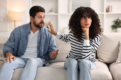 Emotional couple having quarrel on sofa at home. Relationship problems