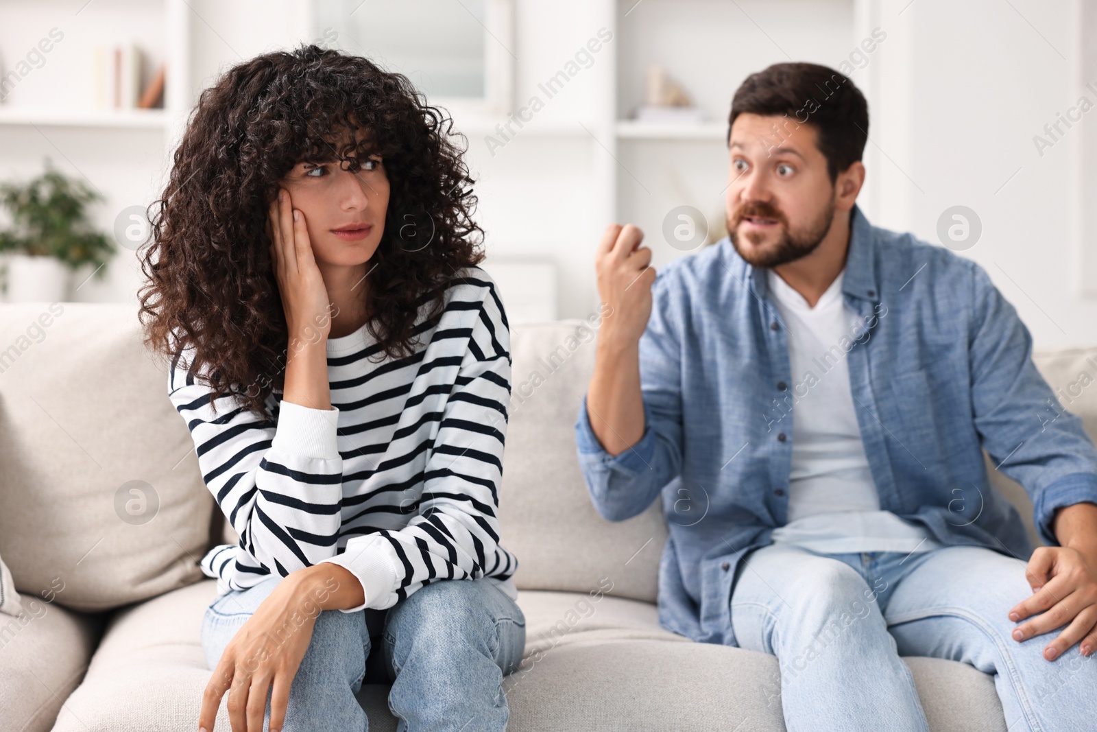 Photo of Emotional couple having quarrel on sofa at home, selective focus. Relationship problems