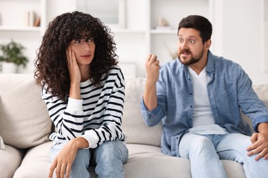 Emotional couple having quarrel on sofa at home, selective focus. Relationship problems