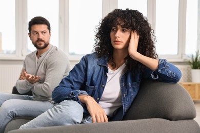 Photo of Emotional couple having quarrel on sofa at home, selective focus. Relationship problems