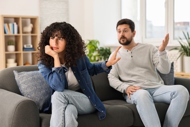 Emotional couple having quarrel on sofa at home, selective focus. Relationship problems