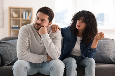 Photo of Emotional couple having quarrel on sofa at home. Relationship problems