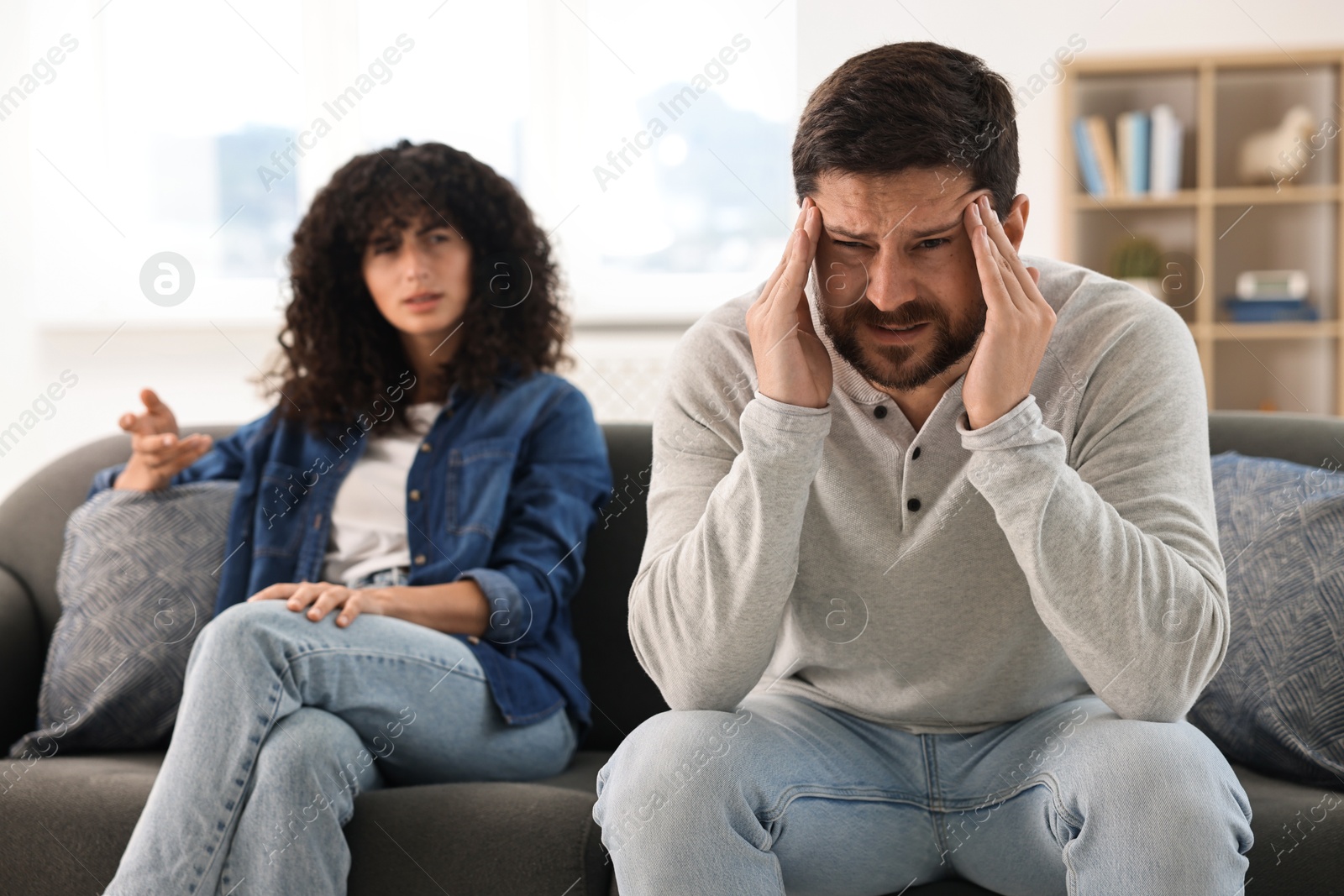 Photo of Emotional couple having quarrel on sofa at home, selective focus. Relationship problems