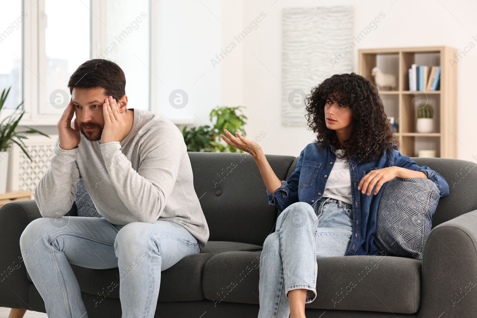 Photo of Emotional couple having quarrel on sofa at home. Relationship problems