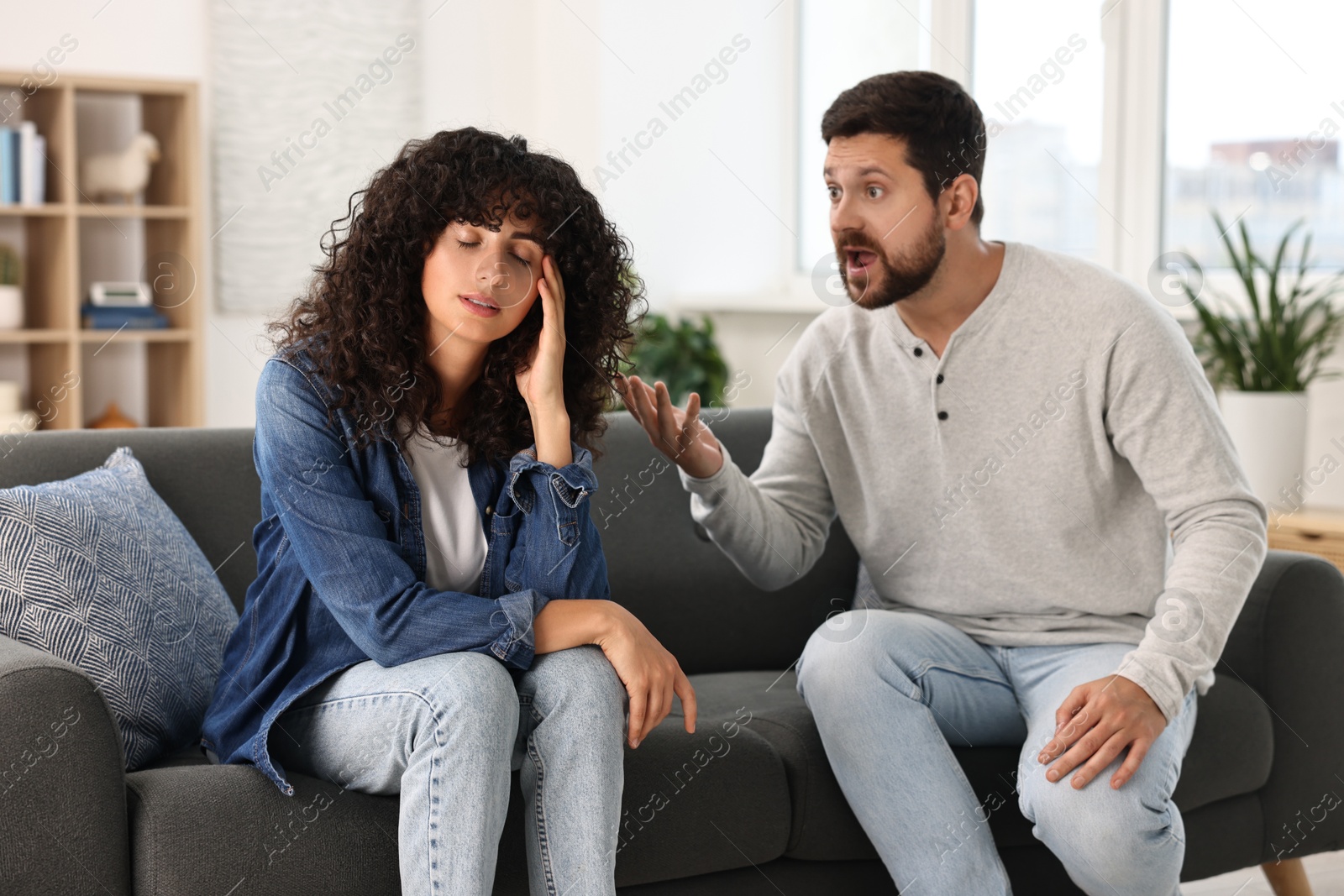 Photo of Emotional couple having quarrel on sofa at home. Relationship problems