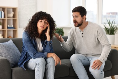 Emotional couple having quarrel on sofa at home. Relationship problems