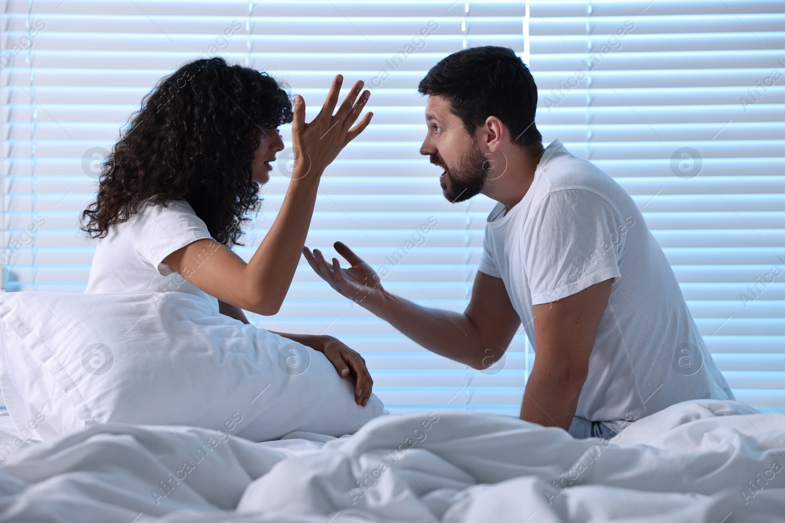 Photo of Emotional couple arguing in bedroom at night. Relationship problems