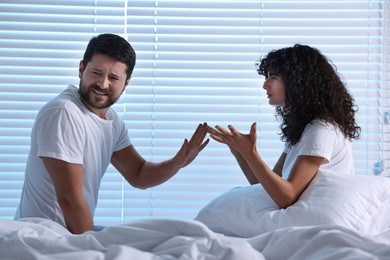 Photo of Emotional couple arguing in bedroom at night. Relationship problems