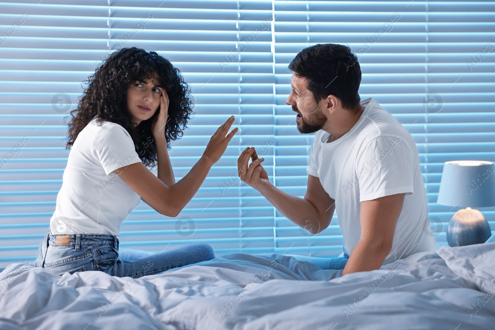 Photo of Emotional couple arguing in bedroom at night. Relationship problems