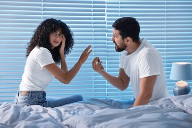 Photo of Emotional couple arguing in bedroom at night. Relationship problems