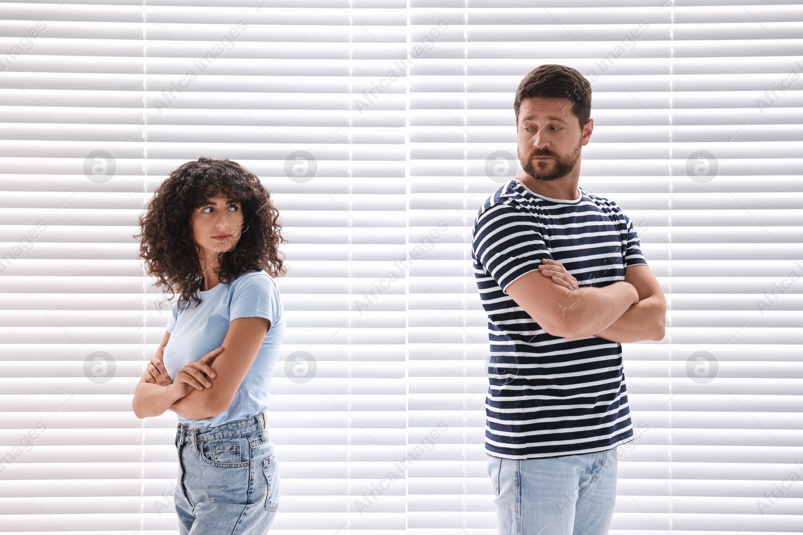 Photo of Couple having quarrel against white blinds. Relationship problems