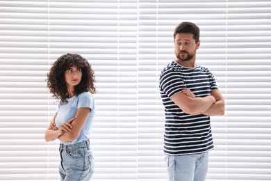 Photo of Couple having quarrel against white blinds. Relationship problems