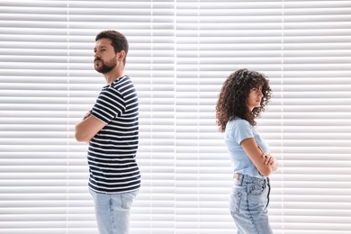 Couple having quarrel against white blinds. Relationship problems