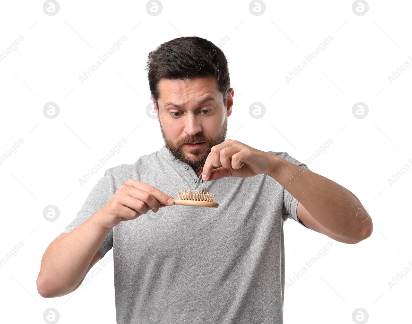 Photo of Sad man taking his lost hair from brush on white background. Alopecia problem