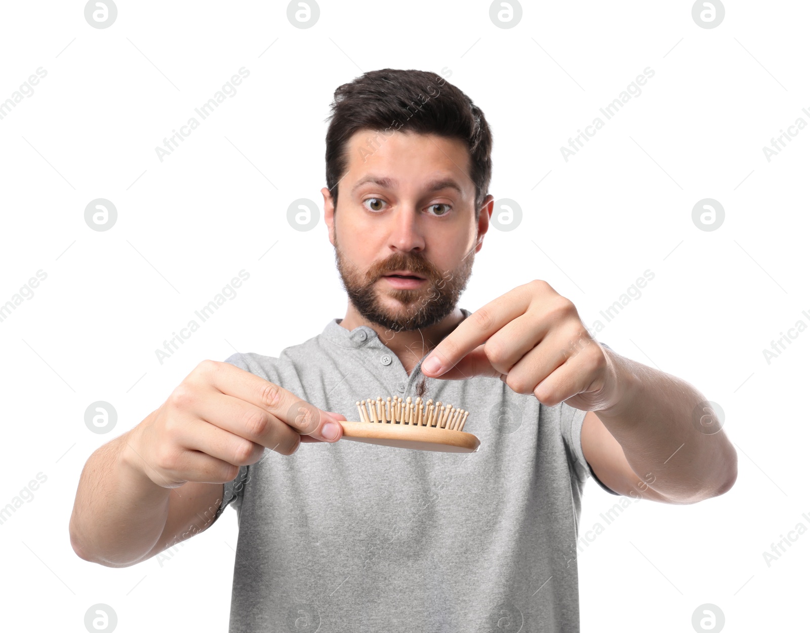 Photo of Sad man taking his lost hair from brush on white background. Alopecia problem