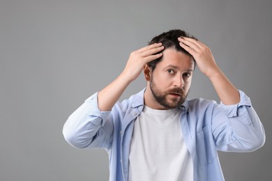 Photo of Man with hair loss problem on gray background, space for text