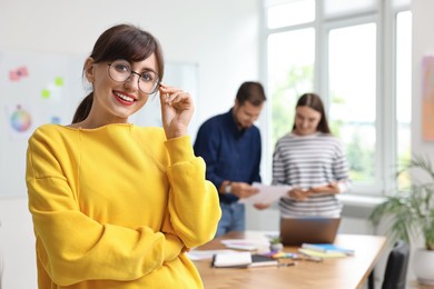 Photo of Portrait of happy young designer with glasses in office