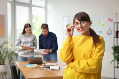 Portrait of happy young designer with glasses in office