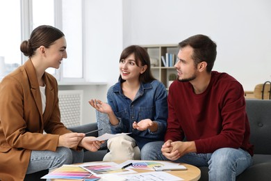 Designer discussing project with clients at table in office