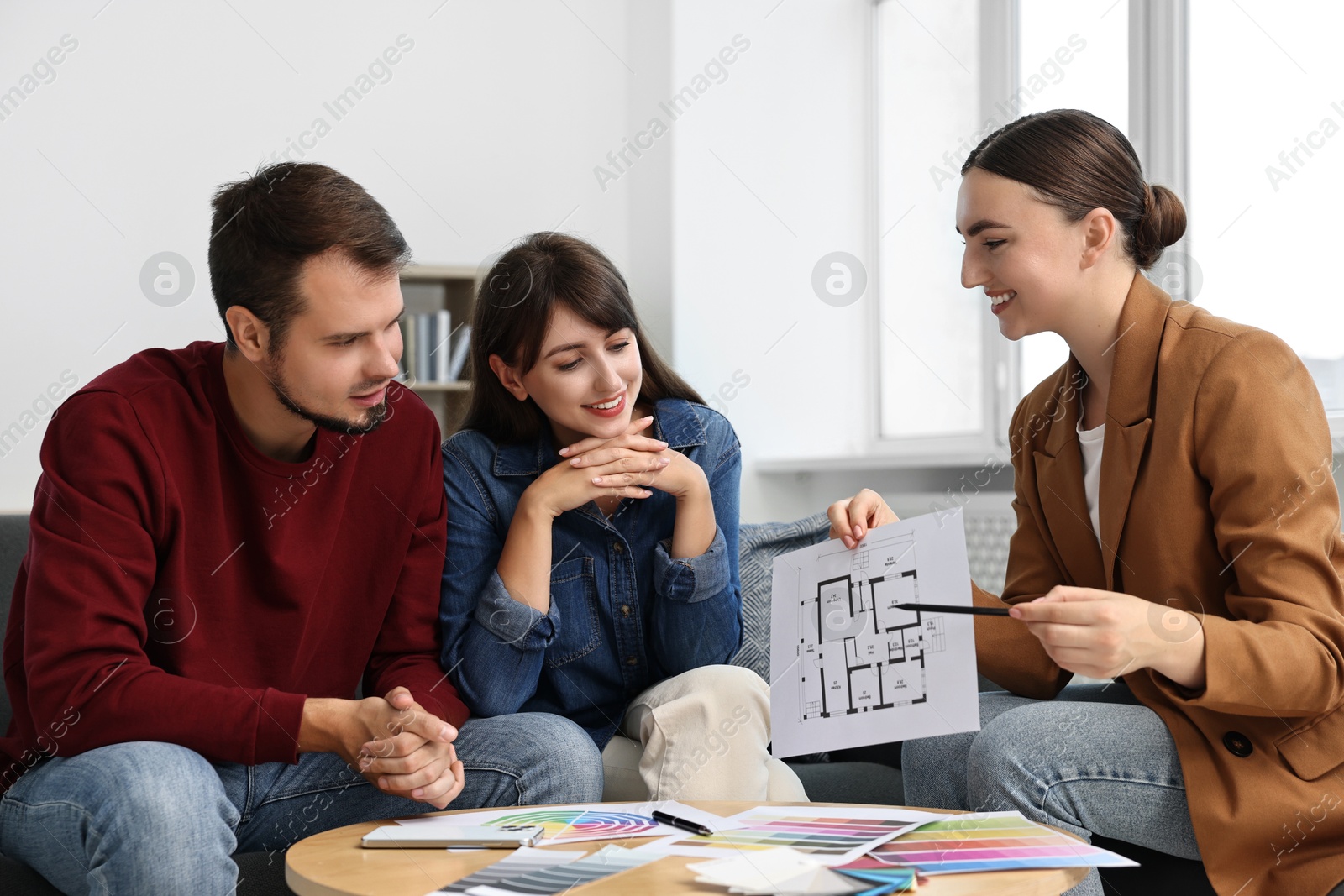 Photo of Designer discussing project with clients at table in office