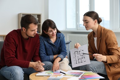 Photo of Designer discussing project with clients at table in office