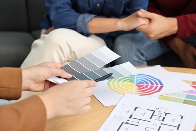 Designer discussing project with clients at table indoors, closeup