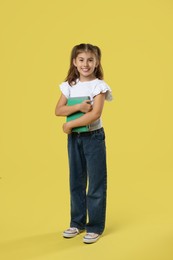 Photo of Positive girl with books on yellow background