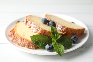 Photo of Freshly baked sponge cake, mint and blueberries on white wooden table