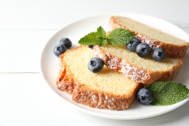 Photo of Freshly baked sponge cake, mint and blueberries on white wooden table