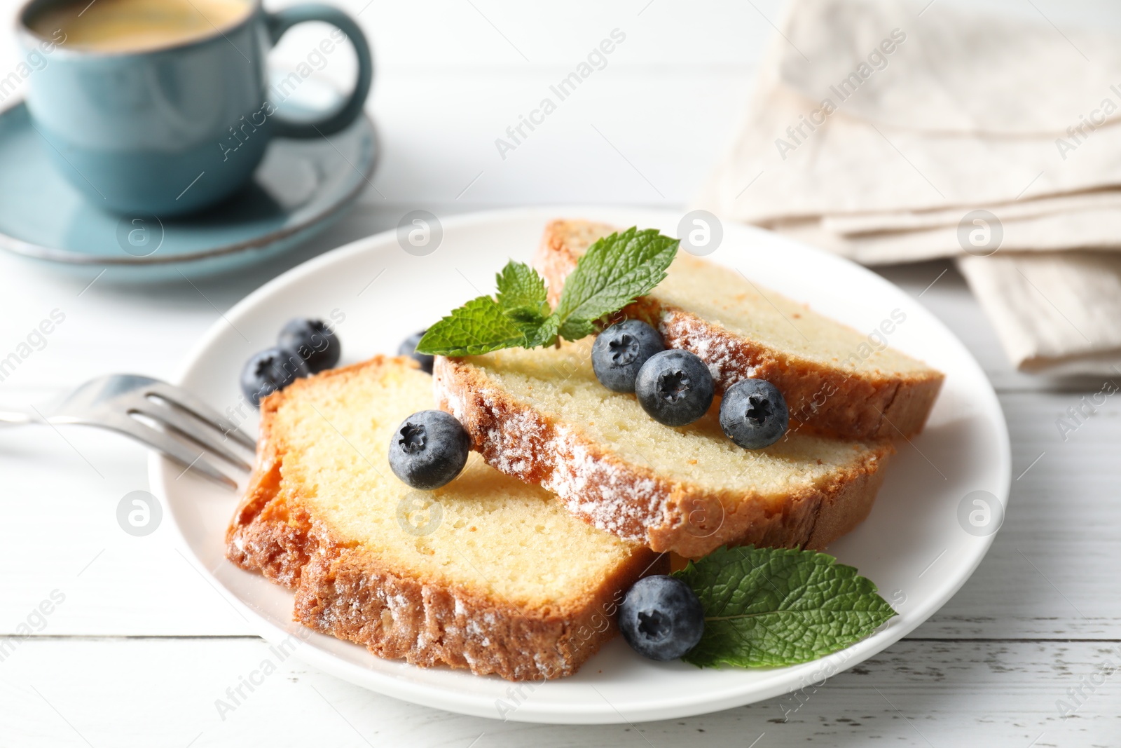 Photo of Freshly baked sponge cake, mint and blueberries on white wooden table