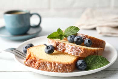 Photo of Freshly baked sponge cake, mint and blueberries on white wooden table, closeup