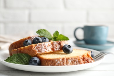 Photo of Freshly baked sponge cake, mint and blueberries on white wooden table, closeup