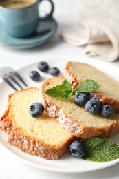 Photo of Freshly baked sponge cake, mint and blueberries on white wooden table, closeup