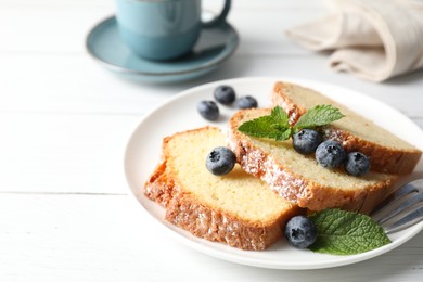 Photo of Freshly baked sponge cake, mint and blueberries on white wooden table