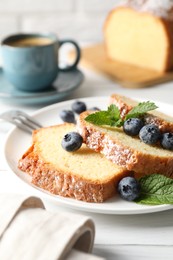 Photo of Freshly baked sponge cake, mint and blueberries on white wooden table, closeup