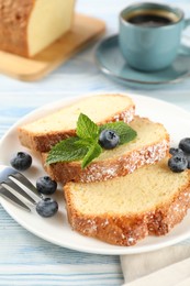 Photo of Freshly baked sponge cake, blueberries and mint on light blue wooden table, closeup