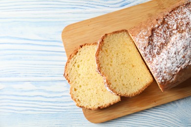 Photo of Freshly baked sponge cake on light blue wooden table, top view. Space for text