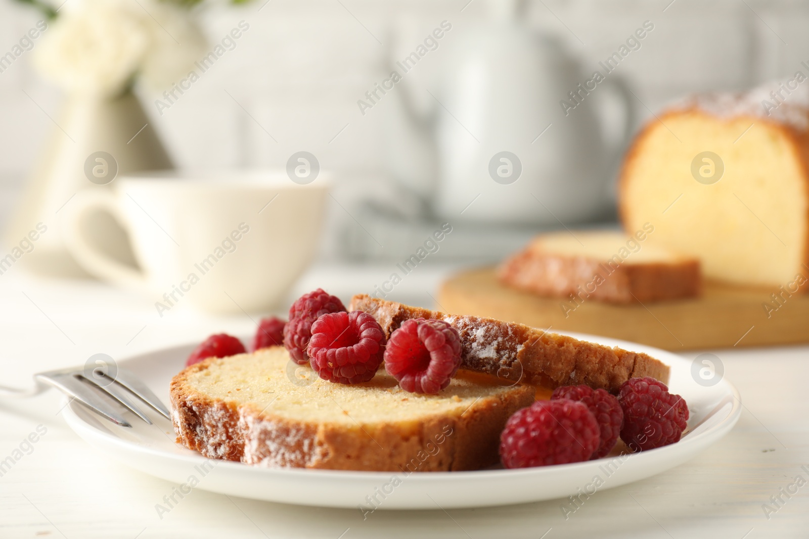 Photo of Freshly baked sponge cake and raspberries on white wooden table, closeup