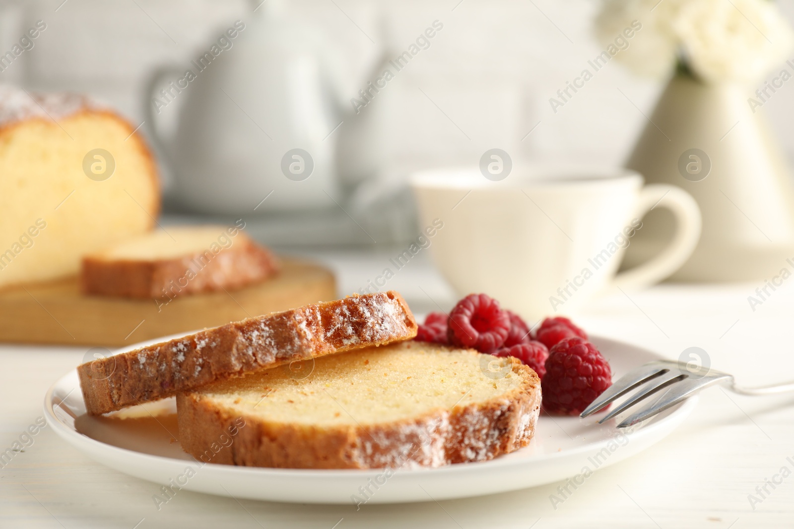 Photo of Freshly baked sponge cake and raspberries on white wooden table, closeup