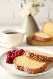 Photo of Freshly baked sponge cake and raspberries on white wooden table, closeup