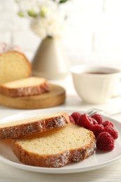 Photo of Freshly baked sponge cake and raspberries on white wooden table, closeup