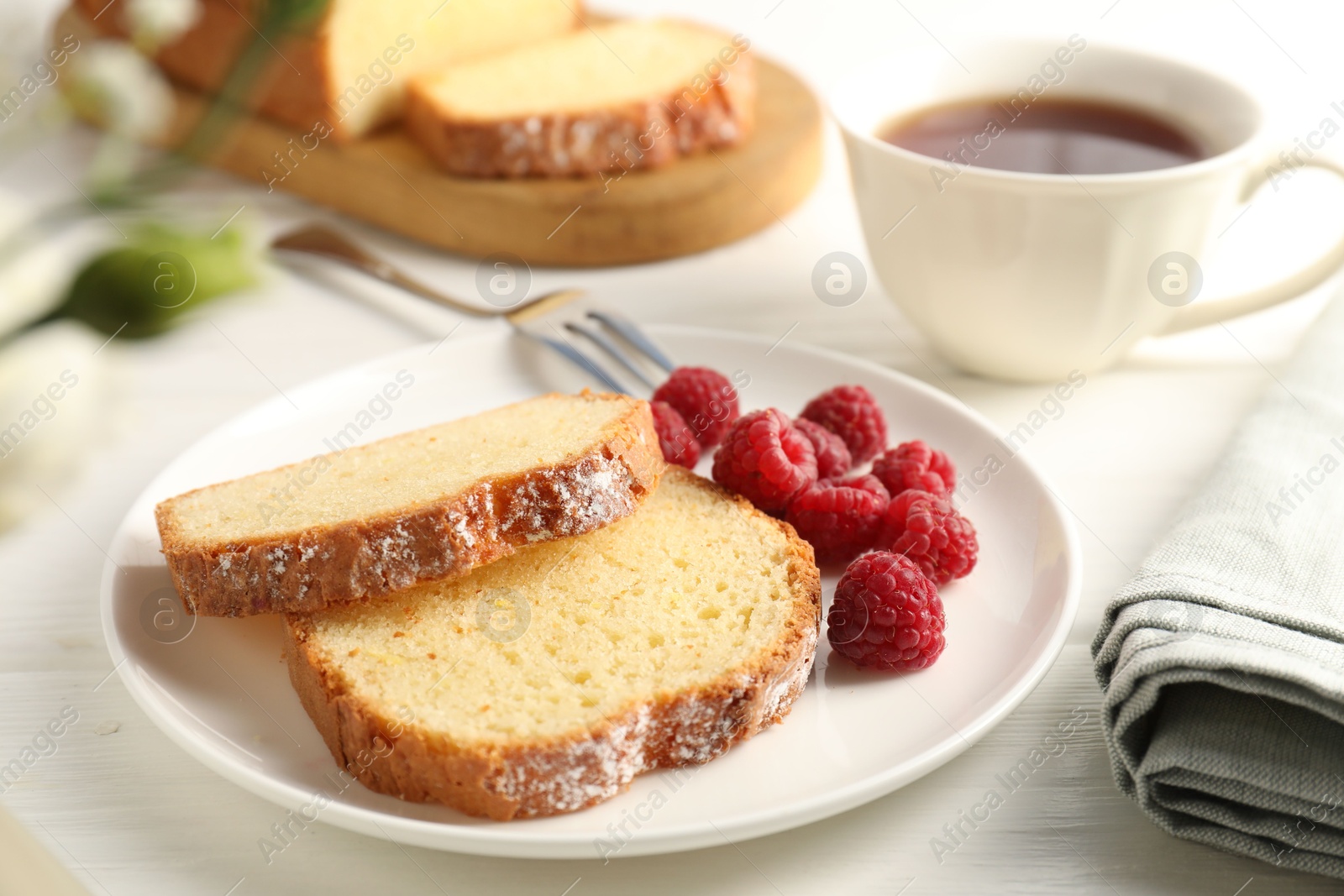 Photo of Freshly baked sponge cake and raspberries on white wooden table