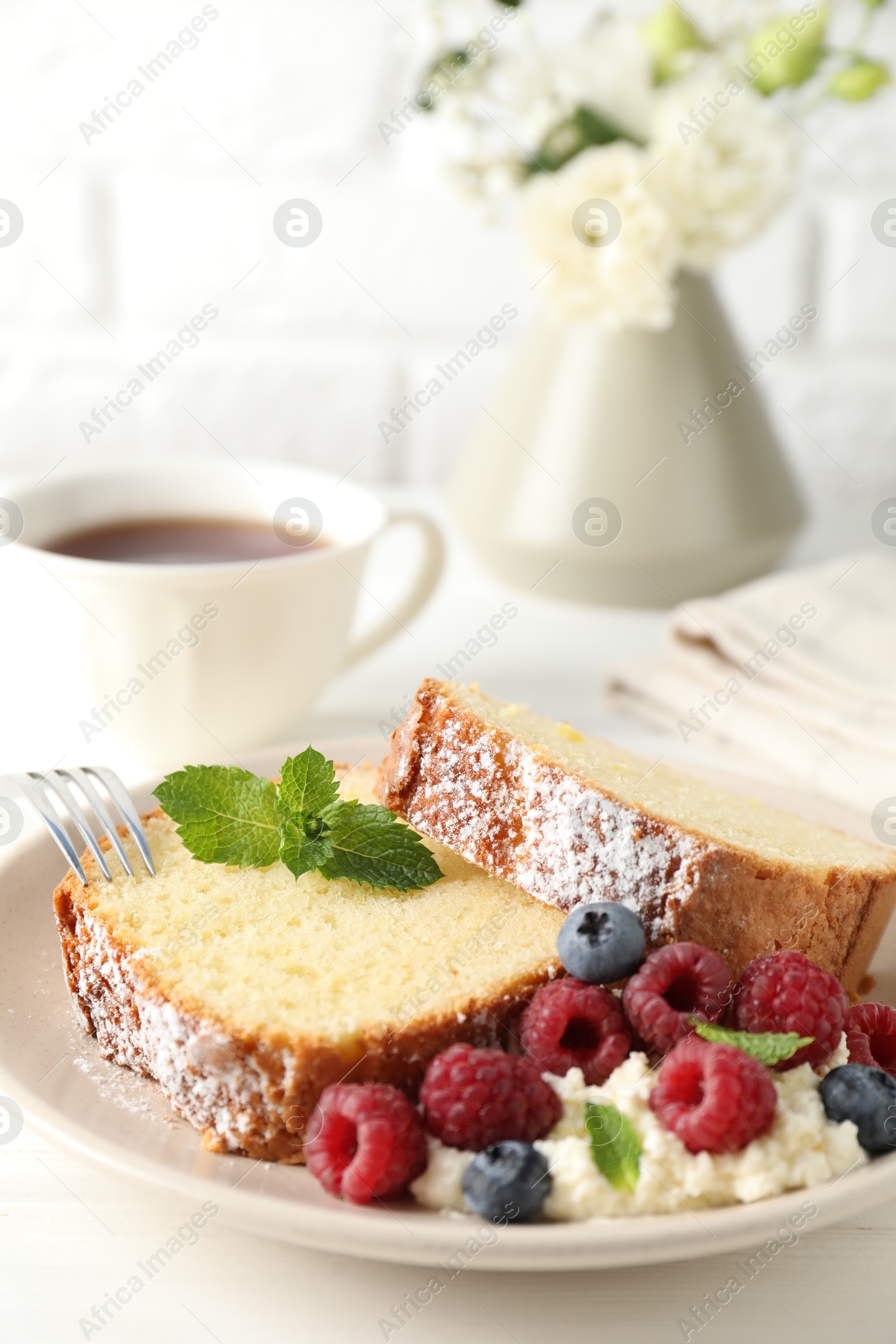 Photo of Freshly baked sponge cake, whipped cream, berries and mint on white wooden table, closeup