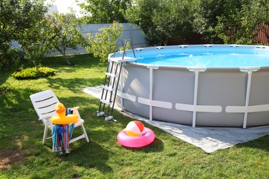 Above ground swimming pool, folding chair, towel, inflatable rings and ball in backyard