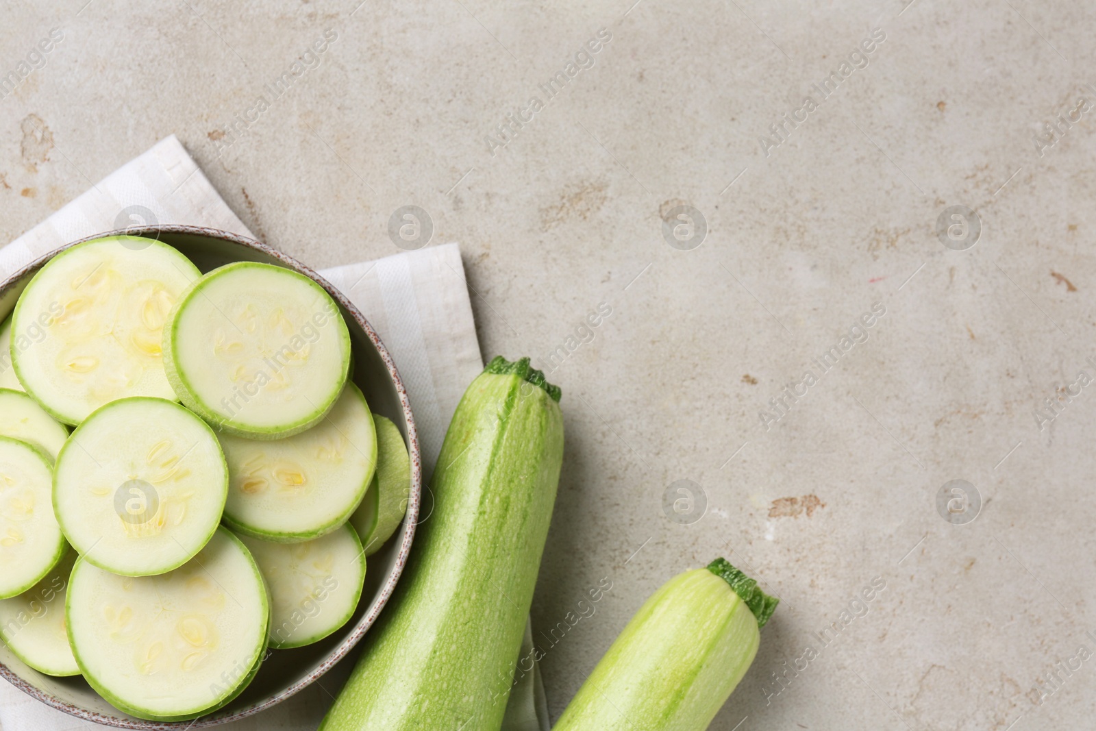 Photo of Fresh cut and whole zucchinis on grey textured table, flat lay. Space for text